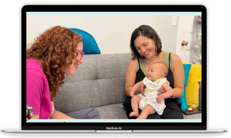 a laptop screen showing a picture of Rachel sitting on a couch, speaking to a smiling baby who is sitting in her smiling mother's lap